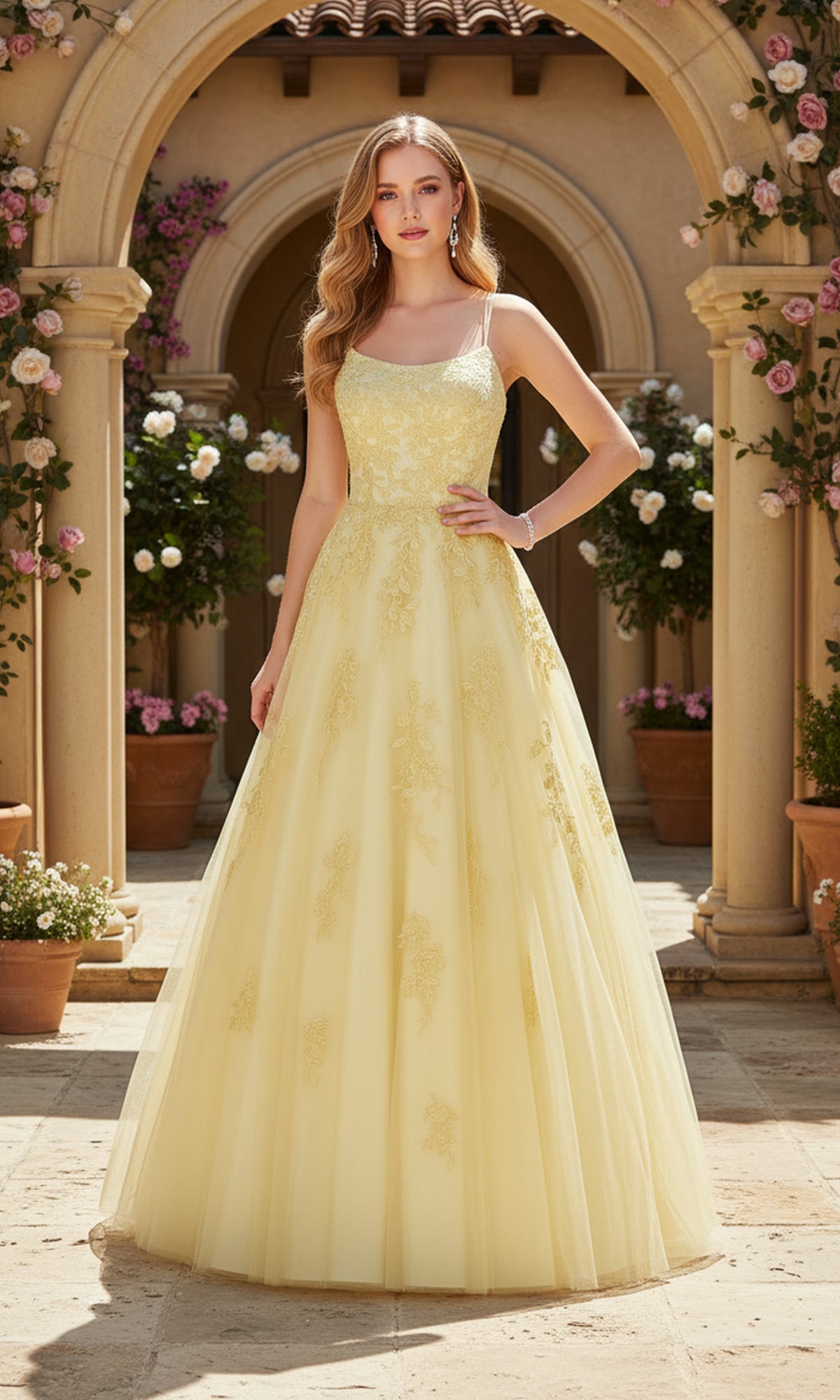 A woman stands outdoors in front of an arched doorway, wearing the PromGirl Exclusive 250228 long prom dress with lace embroidery and an adjustable lace-up back. Potted plants and flowers enhance the charming scene.